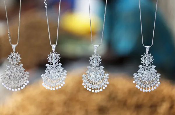 Quatre pendentifs en métal argenté ouvragé avec perles et pampilles, suspendus à des chaînes fines