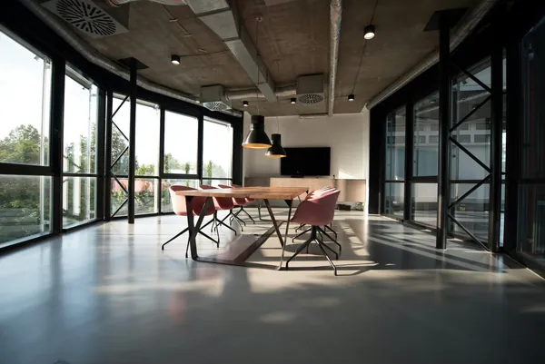Grand bureau vide en open space avec une longue table, des chaises et des baies vitrées