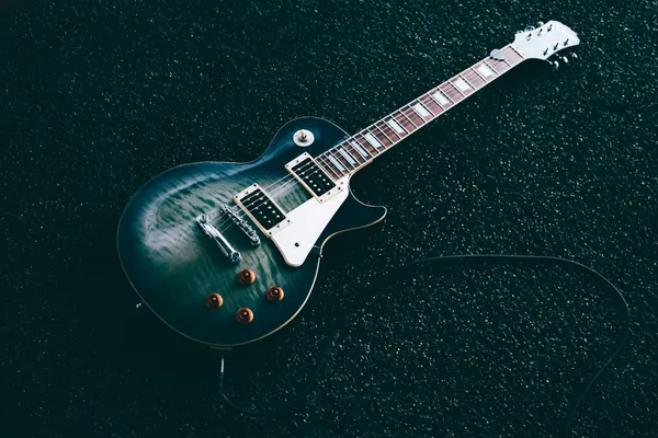 Guitare électrique à corps vert foncé posée à plat, câble branché