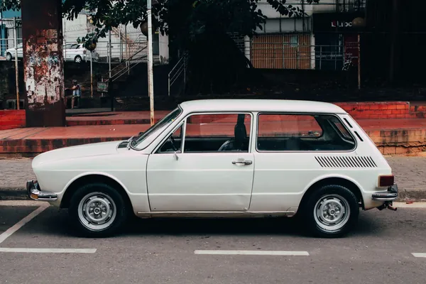 Petite voiture break blanche des années 1970 garée de profil dans une rue